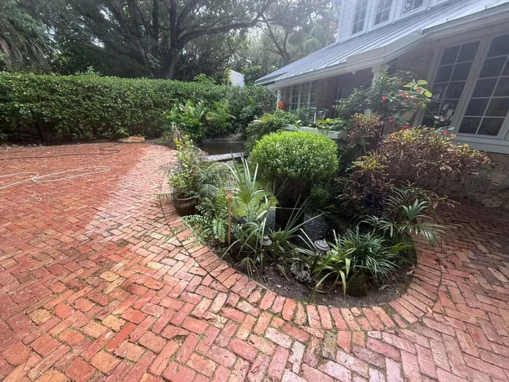 Brick courtyard mid-clean showing dirty and clean pavers
