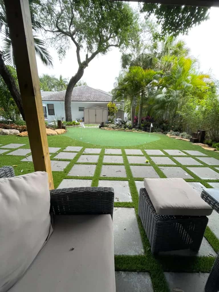 Backyard with large pavers set in artificial turf and a putting green